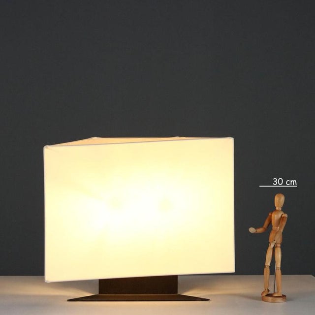 1970s table lamp with enamelled steel base and fabric lampshade. Good condition. This piece is attributed to the mentioned...