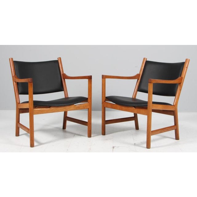 Hans J. Wegner pair of lounge chairs with frame of oiled oak. Upholstered with black leather. Model CH52, made by Carl...