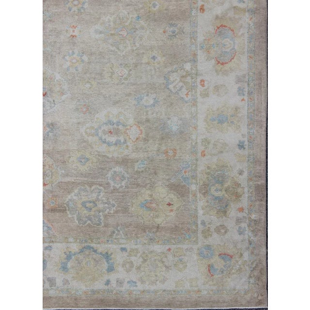 This hand Knotted, hand spun Oushak rug from Turkey features a subdued, neutral color palette and an all-over design of...