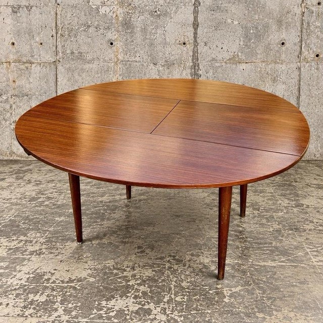 A stylish mid-century oval extending dining table by renowned British furniture manufacturer Greaves & Thomas, featuring...