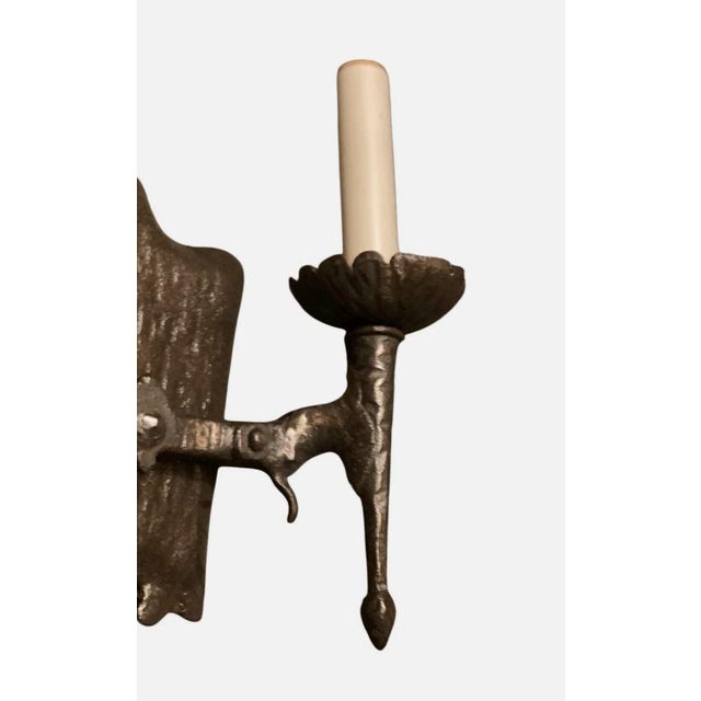 This is a vintage wrought iron wall sconce with a Gothic aesthetic. The backplate has an irregular, hand-hammered...