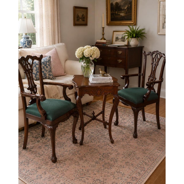 Elegant pair of vintage Chippendale-style armchairs featuring richly carved wood frames, pierced decorative splat backs,...