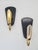 A striking pair of modernist-style wall sconces from the 1970s, crafted from black lacquered metal and brass accents. The...