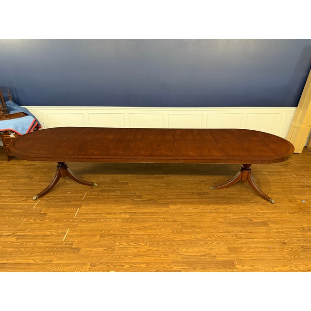 This is a Traditional Oval Banded Mahogany Dining Table by Leighton Hall Furniture. It features a field of swirly crotch...