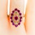 This Vintage 14K Yellow Gold Ruby Ring in Size 8 has a tapered shank that features an openwork scroll motif, connected to...