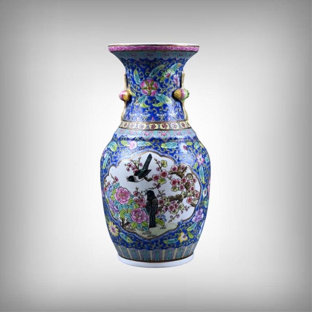 This Chinese porcelain vase, decorated in the Famille Rose style, presents a delicate scene of birds perched on flowering...