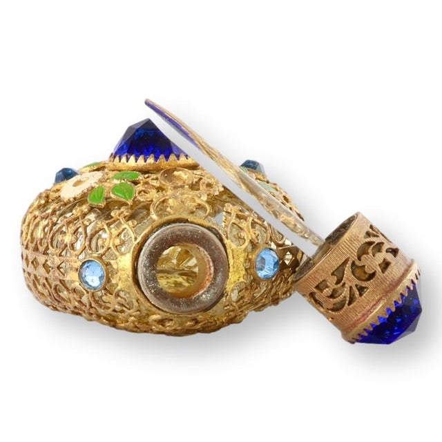 Ornate midcentury ormolu scent bottle, featuring elaborate openwork filigree decoration accented with faceted blue glass...