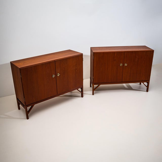 Pair of sideboards, each with two doors and refined brass fittings and handles. The cabinets stand on square legs with...