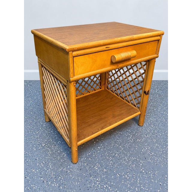 Charming vintage bamboo and rattan nightstand featuring a warm honey-toned finish and beautiful lattice detailing along...
