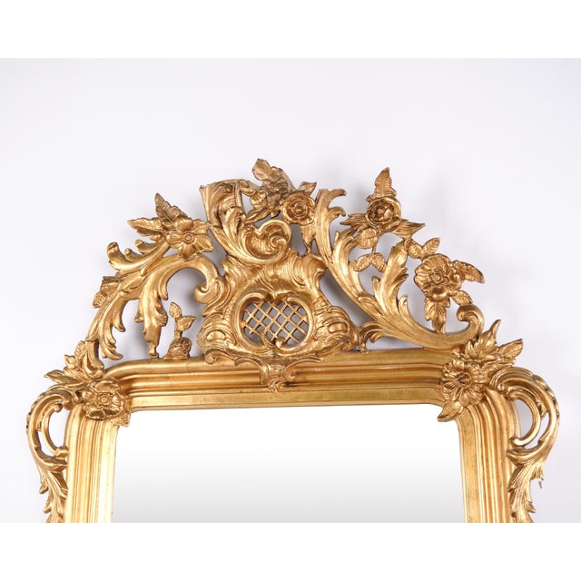 Large antique french wall mirror in louis xv rococo style from the 19th century. The mirror features a richly decorated...