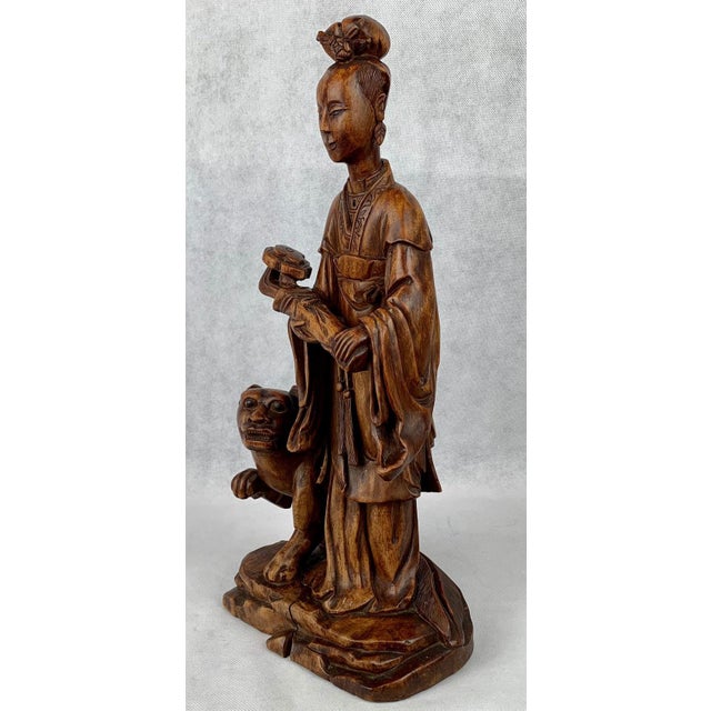 Chinese carved teak female figure with a removable head. She holds a Ruyi (scepter) in her hands and has a dog at her...
