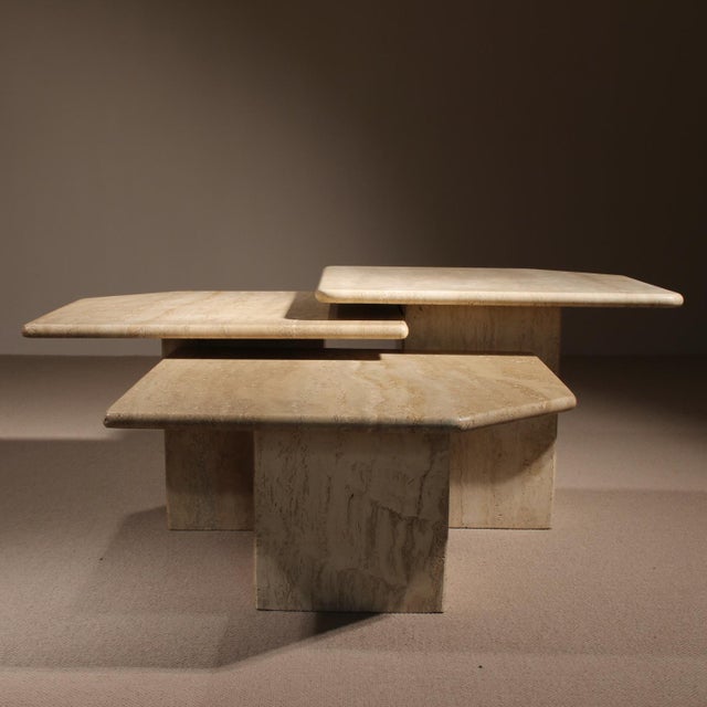 A striking set of three nesting tables crafted from solid travertine in a light, sandy hue. The minimalist 1970s design...
