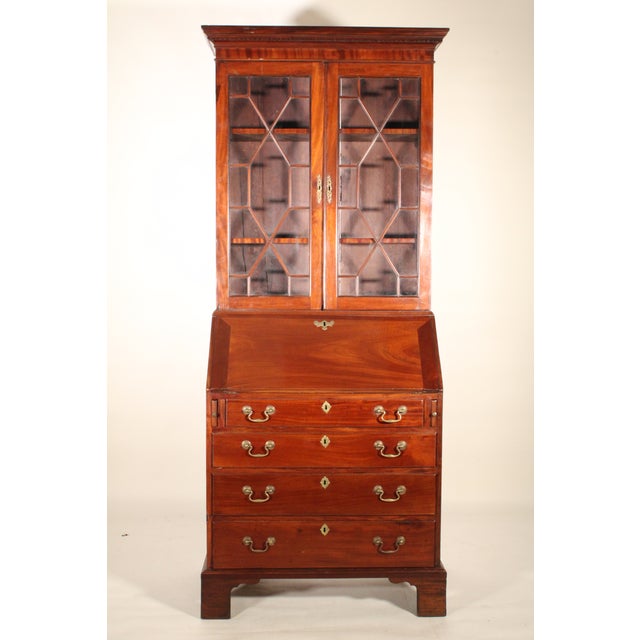 George III mahogany secretary, circa 1800. The pediment with dental moldings, two glass doors with through mullions, a...