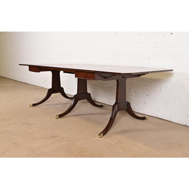 An exceptional Georgian or Regency Revival style carved mahogany drop-leaf extension dining table In the manner of Drexel...