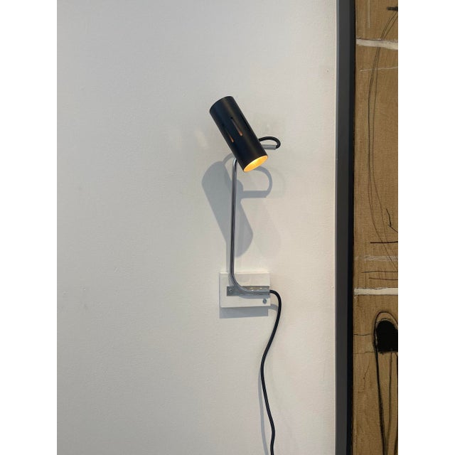 A striking pair of Mid-Century Modern inspired wall sconces, combining slim polished chrome stems with sculptural black...