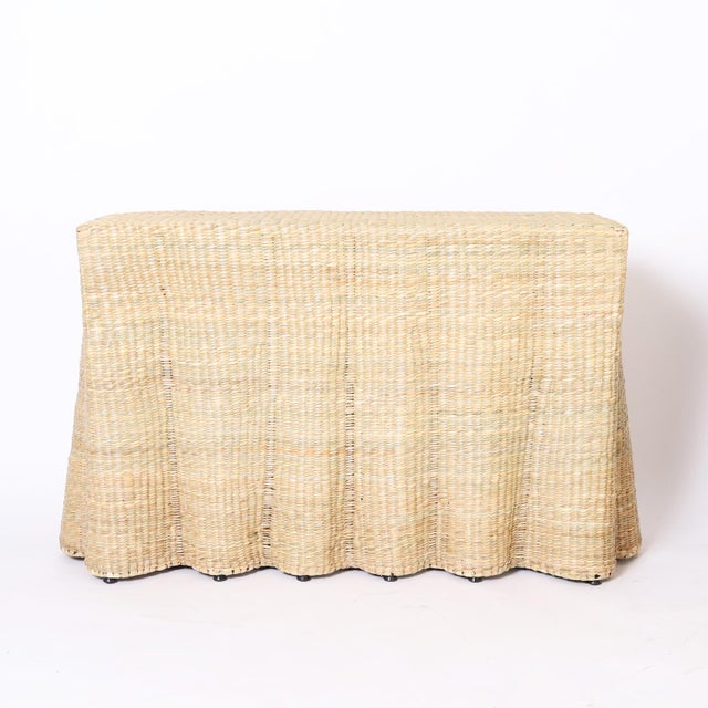 A mid century inspired ghost drapery console with a flat back crafted with a durable metal frame wrapped in reed.