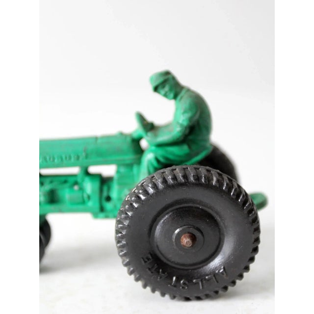 This is a vintage Auburn Rubber Company toy tractor. Dating to the 1950s, the green hard rubber toy tractor features "All...