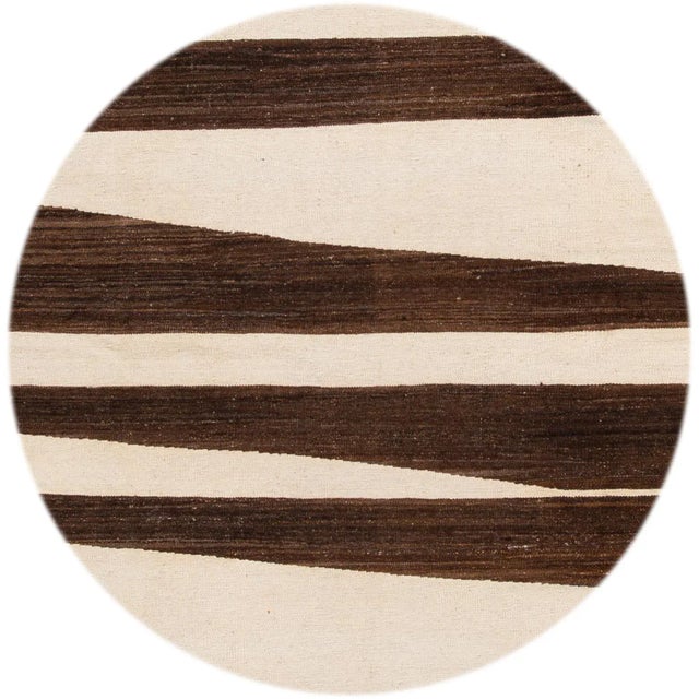 Beautiful hand-knotted wool, modern Kilim rug. This rug has ivory and brown striped field all-over. This rug measures 10'...