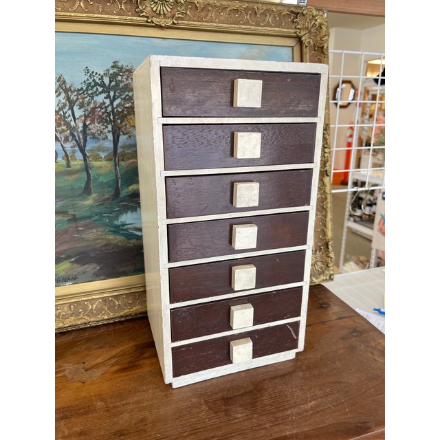 A mid-century modern jewelry chest created by M.I.M. Ladoring of New York, featuring seven pull-out drawers. The case is...