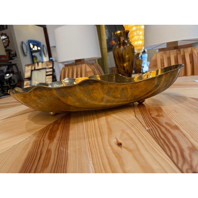 Decorative brass tray featuring an elongated shell-inspired silhouette, flowing raised ribs, and a softly scalloped rim....
