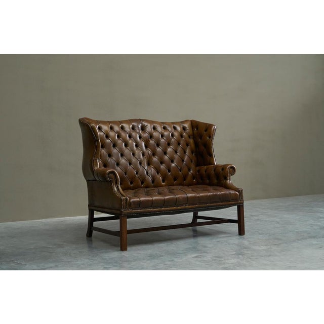 Highly Original Tufted English Wingback Settee in Patinated Leather England Early 20th Century A handsome and rare English...