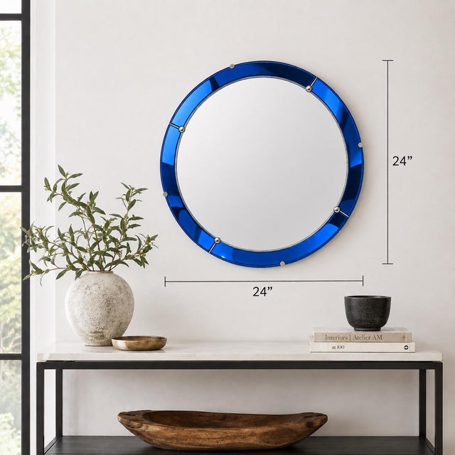 Striking round wall mirror featuring a rich cobalt blue glass surround accented with polished metal details. The segmented...