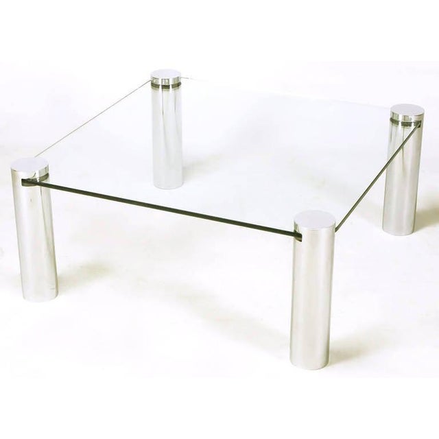 Unusual chromed four cylinder and glass square coffee table. Four chromed steel cylinders have notched openings with...