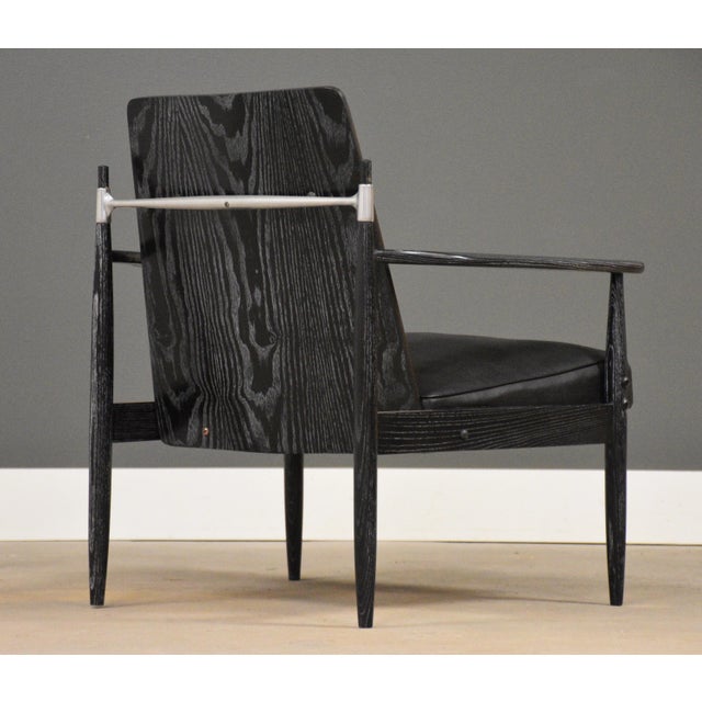 A mid century modern black cerused lacquer ebonized lounge chair with black vinyl upholstery and a stainless steel back...
