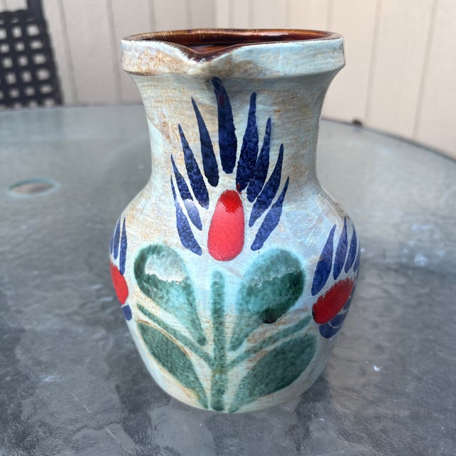 This is a vintage 1970s St. Clément French barbotine ceramic pitcher. It features a hand-painted stylized floral design in...