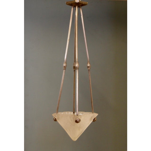 Art Deco pendant light with geometric motifs in the glass shade and metal fixture, which is in perfect condition. The...