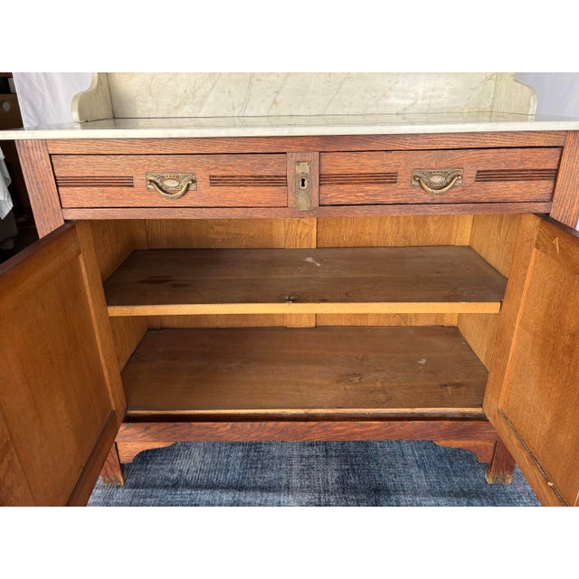 French antique oak washstand / vanity with a marble top, oval beveled mirror, and floral carvings. Excellent condition. No...