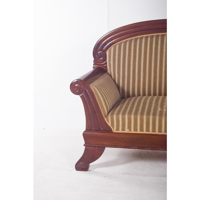 Canapé, upholstered in striped fabric. with a rounded backrest, it is surrounded by a carved frame with a volute design on...