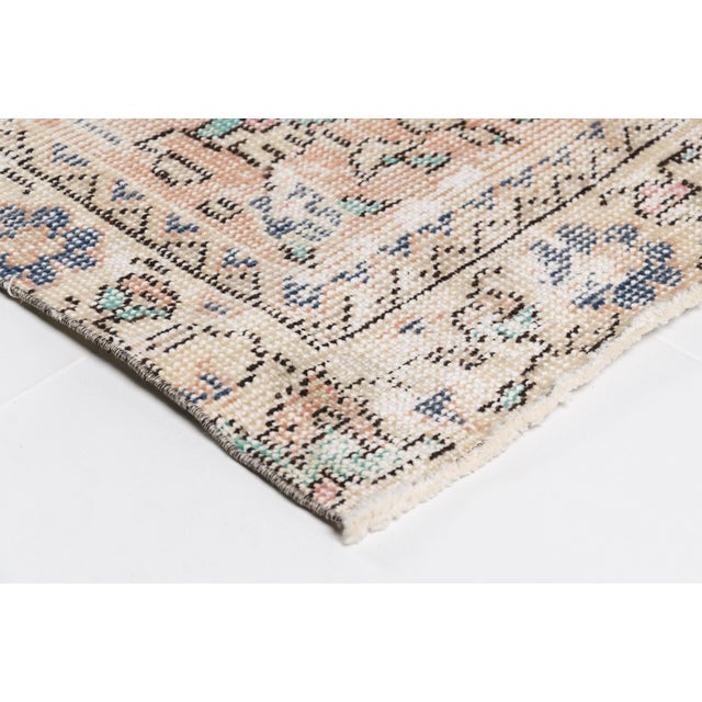 This is a vintage Turkish Oushak rug from the Mid 20th Century. The piece was hand-knotted.