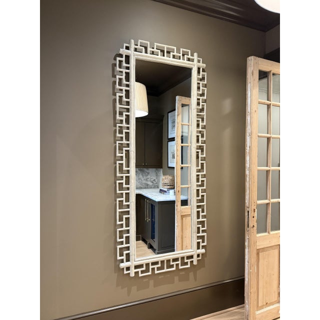 An oversized Hollywood Regency wall mirror featuring an architectural Greek Key frame with deep relief detailing. The...