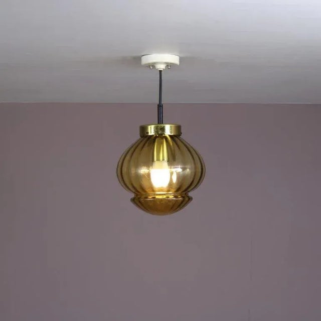 A beautiful hanging lamp manufactured by Raak in the Netherlands around 1960. It is made of high quality glass amber...