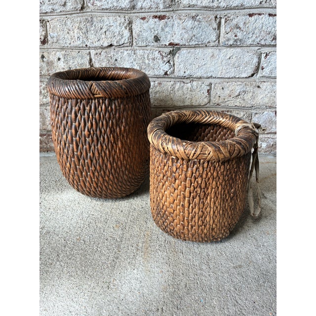 Pair of small scale rustic Chinese woven baskets featuring a rich, dark patina and thick braided rolled rims. The texture...