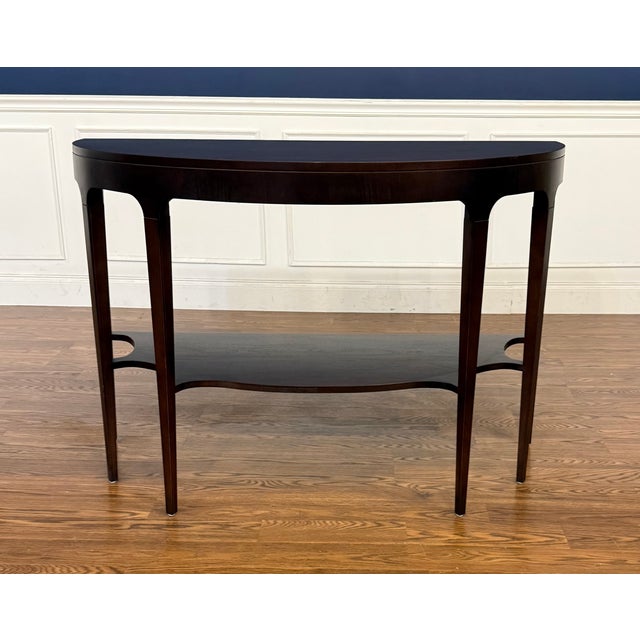 This is the Atlantic Demilune Console by Highland House Furniture. It features a rounded front with a lower shelf. It has...