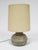 A delightful design, this table lamp features a ceramic base that has a richly textured and patterned surface. It is...