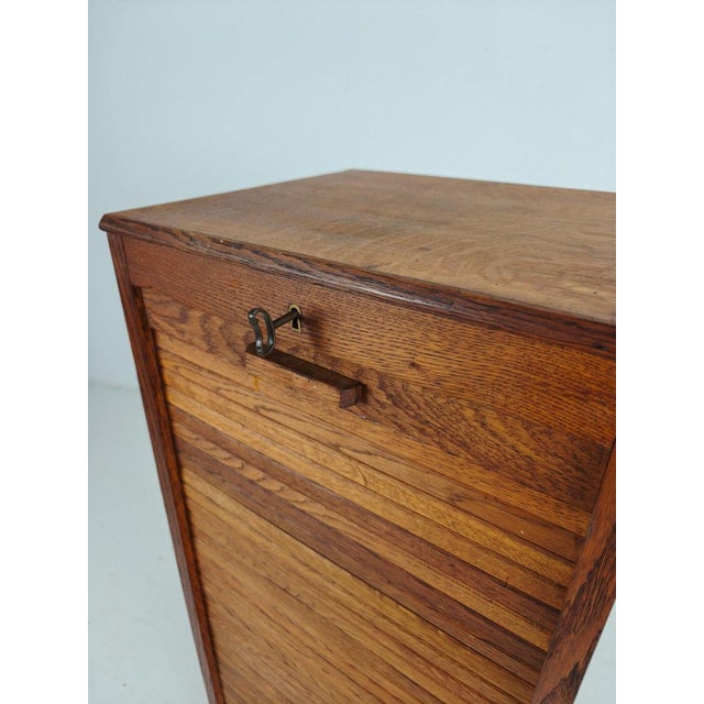 Beautiful and authentic 1940s Dutch oak archive cabinet with a smooth-running tambour (roll-top) door. A true piece of...