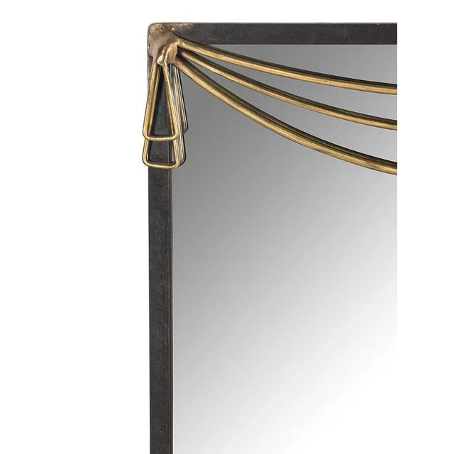 Sleek contemporary wall mirror crafted in patinated metal, accented with a sculptural draped brass detail along the upper...