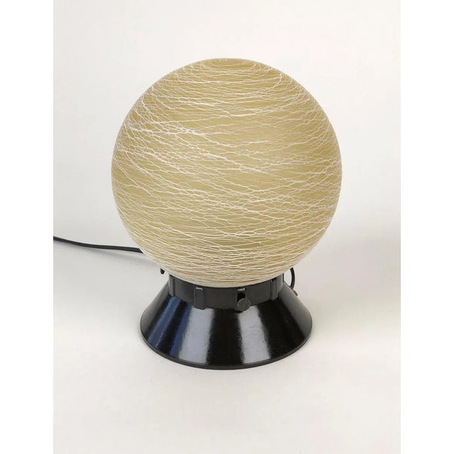 Austrian table lamp from the 1930s, is composed of a Bakelite base with a glass ball. The pattern on the ball is made up...