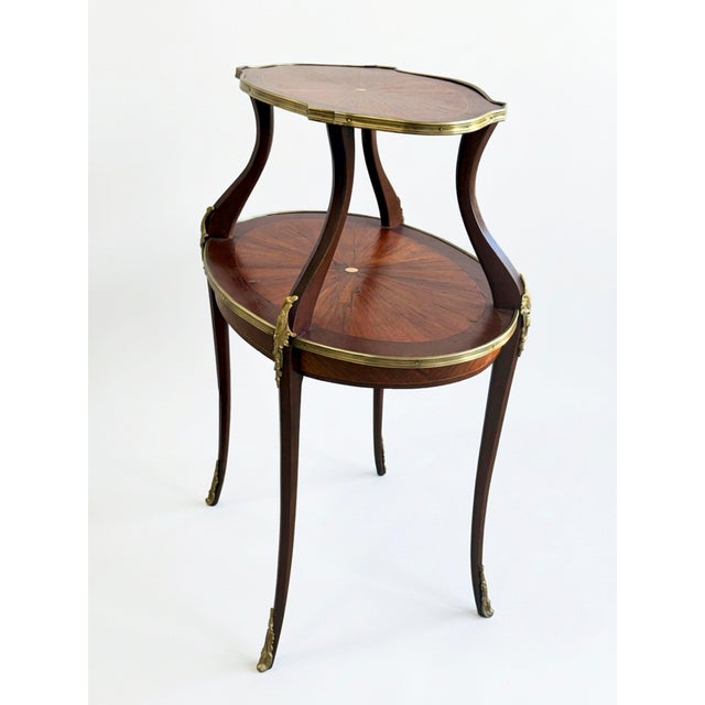 Elevate your space with this vintage French Louis XV style two-tier étagère table, an exquisite blend of fine artistry and...