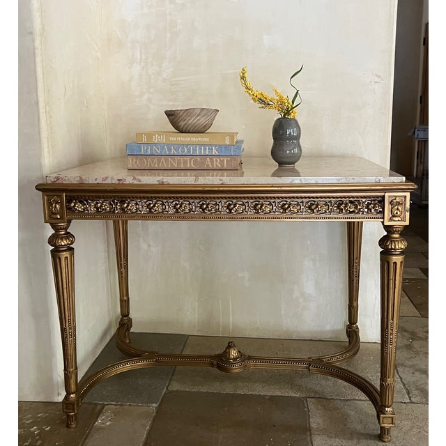 French veined marble topped table which includes floral open work frieze on all sides and carved fluted legs. Made in the...