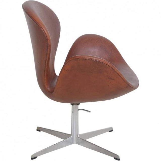 Arne Jacobsen Swan chair upholstered in patinated anilin leather, and with an aluminium base. The chair is from 1969 and...