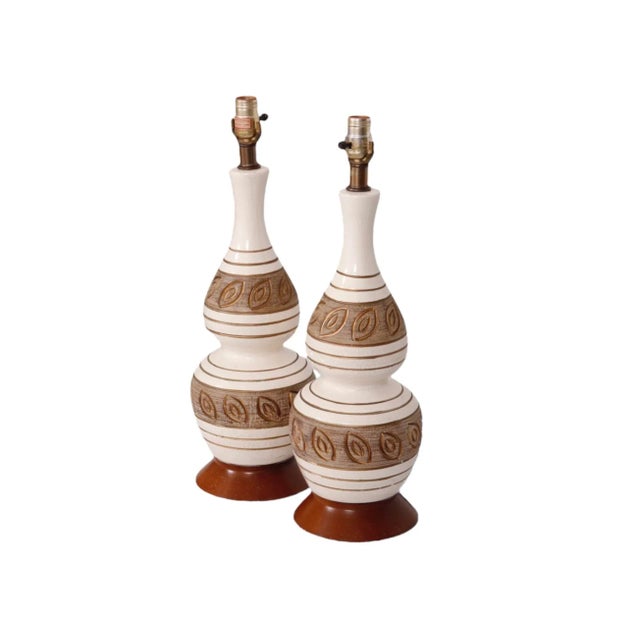 A pair of mid century baluster shaped ceramic and teak table lamps. Finished in a white craquelure glaze, hand decorated...