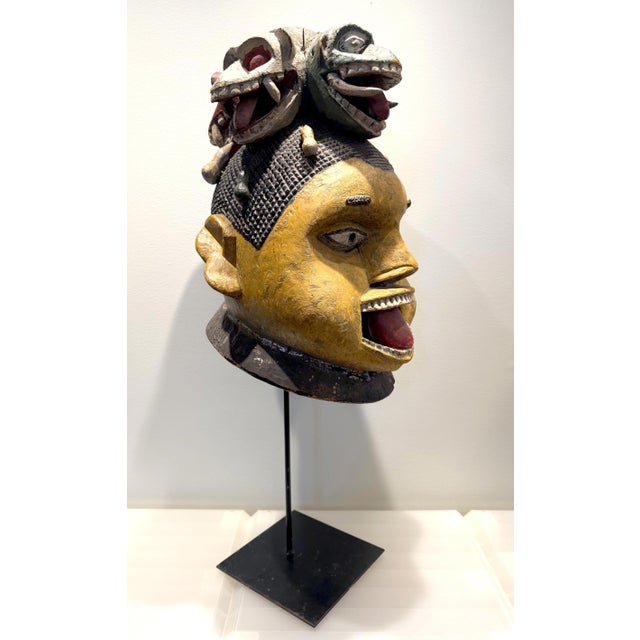 A striking carved wood Yoruba Gẹ̀lẹ̀dẹ́ Helmet Mask on custom display stand circa mid-20th century. From Nigeria, Africa,...