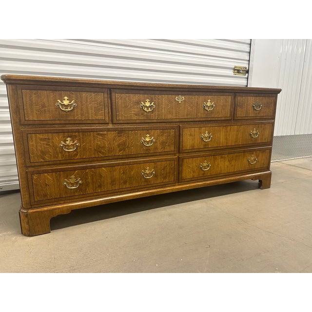 A stunning seven-drawer chest by Baker Furniture. Constructed of tiger oak with black lacquer inlay along the perimeter of...