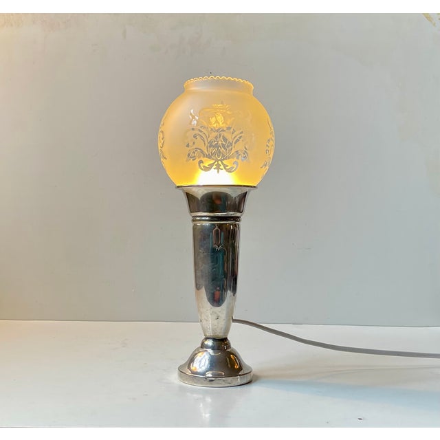 A small restaurant table light executed in silver plated brass and featuring a spherical shade in etched hand-blown glass....
