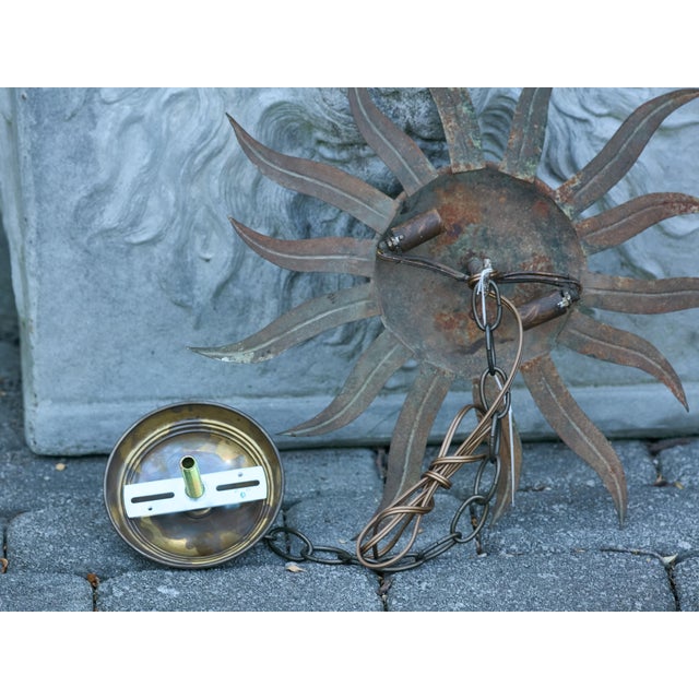A Spanish gilt metal sunburst light fixture from the Midcentury period with wavy rays. This stunning Spanish gilt metal...