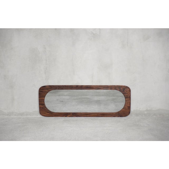 This tall wall mirror was made in Denmark during the 1950s. The rectangular mirror frame with flowing edges is made of...